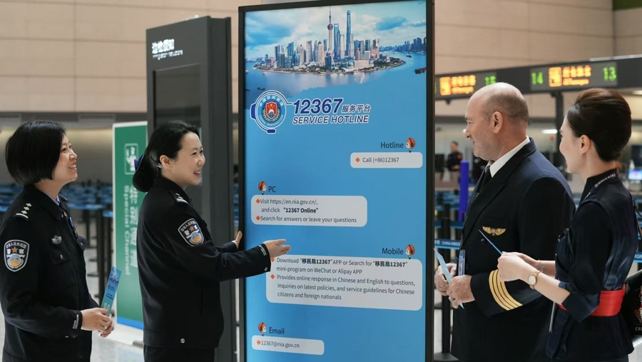 Una funcionaria de inmigración presenta la línea directa del servicio de inmigración 12367 a los miembros de la tripulación de una aerolínea..jpg