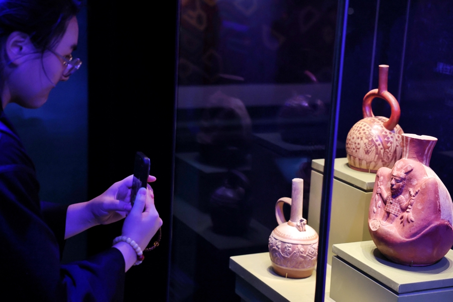 Una visitante toma fotografías de algunas de las piezas presentadas en la exposición En la cima del árbol del mundo-civilizaciones antiguas de América, el 8 de julio en Shanghai..jpg