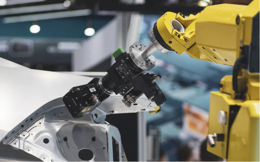 Un robot industrial opera con componentes de automóviles.png