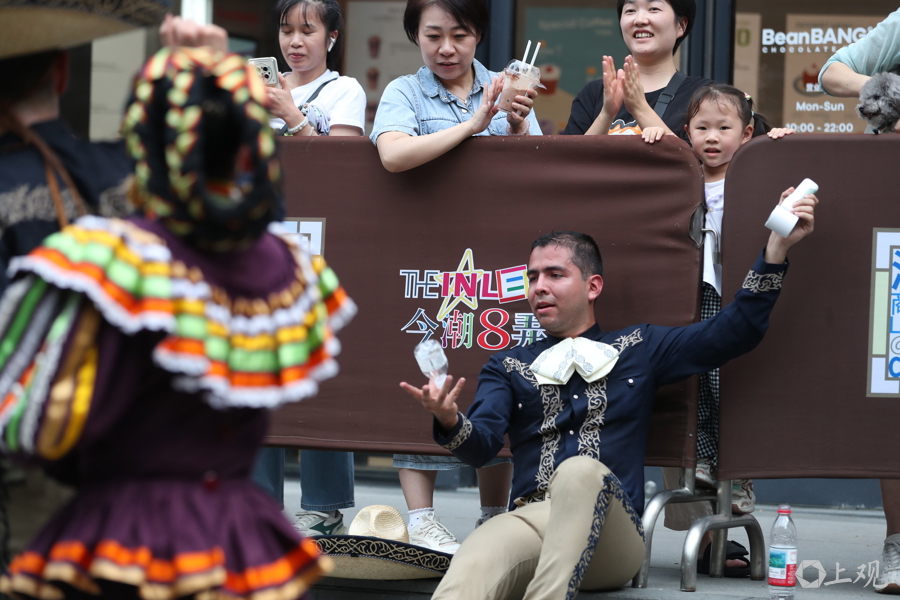 Las espectadoras tienden la mano a un bailarín mexicano, ofreciéndole pañuelos y un ventilador portátil para combatir el calor..jpg