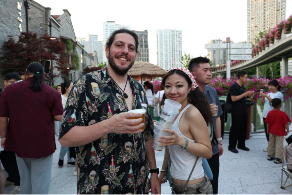 El visitante español Enrique Javier Gallardo Aguilar y su amiga Fang Jingyi degustan cervezas artesanales en el festival.png