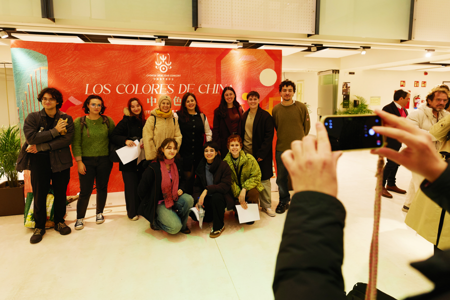 Espectadores jóvenes posan para tomar una foto grupal ante el cartel del concierto..jpg