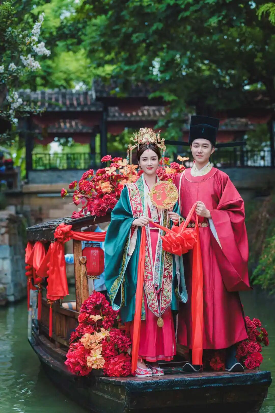 Artistas vestidos con trajes de boda tradicionales chinos posando en la proa de un bote..jpg
