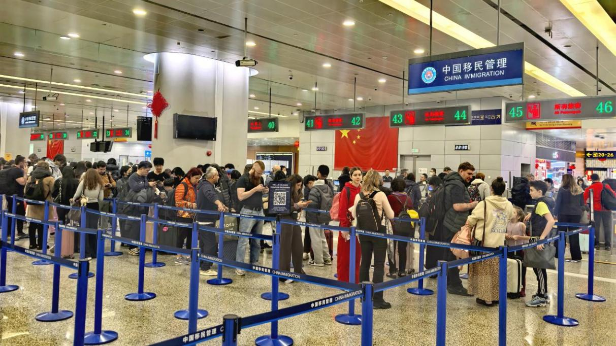 Los viajeros entrantes hacen fila ante el control fronterizo en el Aeropuerto Internacional Pudong de Shanghai..png