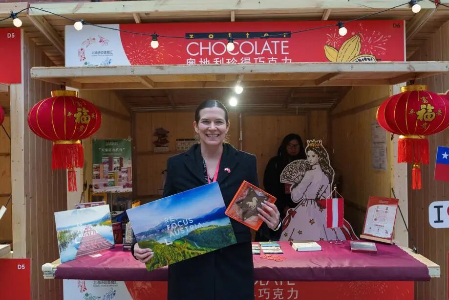 Teresa Bauer, cónsul general interina de Austria en Shanghai, posa para una foto frente al estand que muestra las especialidades de su país natal en la feria..jpg