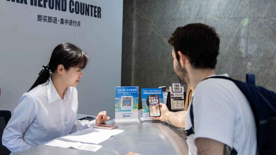 Un viajero internacional utiliza su teléfono móvil para solicitar el reembolso de impuestos en un mostrador de devolución de impuestos.jpg