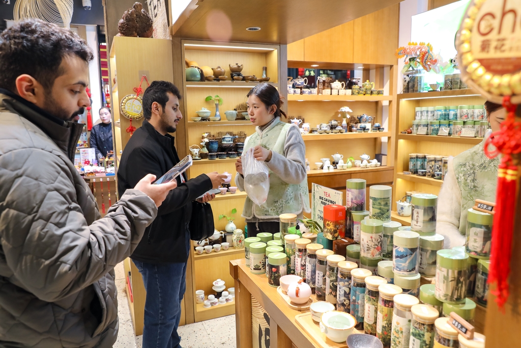 Viajeros internacionales compran artesanías en el Jardín Yuyuan de Shanghai..jpg