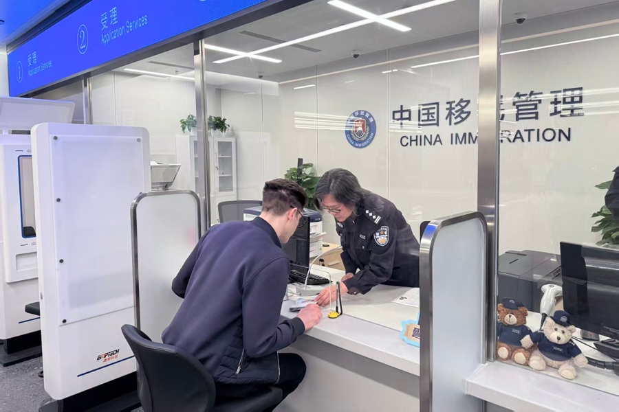 Una funcionaria de inmigración atiende a un viajero de negocios en la Zona de Cooperación Empresarial Internacional del Centro Oriental de Shanghai..png